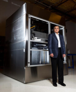 Suman Das, founder and CEO of DDM Systems, standing next to the LAMP 3D printer.